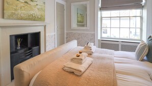 Una habitación de hotel con cama, chimenea, ventana con vistas y obras de arte en las paredes.