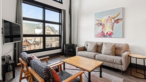 A modern living room with a sofa, coffee table, and a painting of a cow. - Loft on Main St, Access to All Mountain Activities (Frisco)