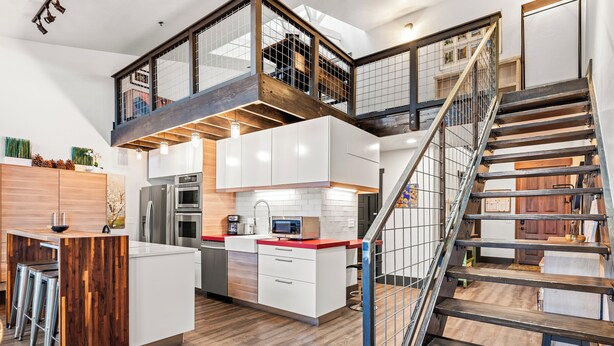 A modern kitchen with a central island, stainless steel appliances, and a wooden staircase. - Loft on Main St, Access to All Mountain Activities (Frisco)