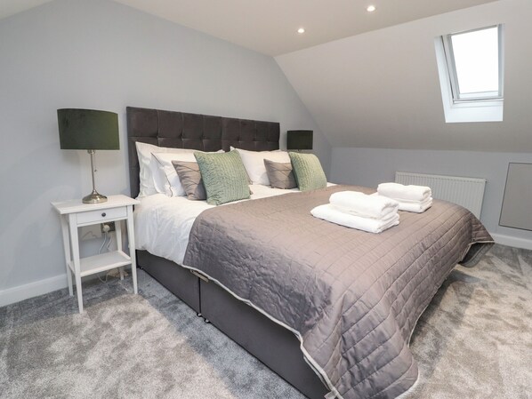 A bedroom with a bed, nightstands, a window, and a radiator. - The Bungalow at 46 Church St (Chorley)