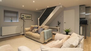 A modern living room with a sofa set, a staircase, and a radiator. - The Bungalow at 46 Church St (Chorley)