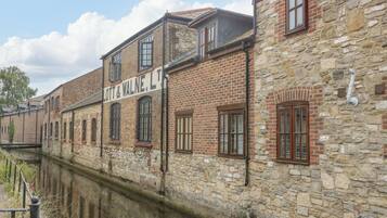Un edificio histórico con fachada de piedra y varias ventanas, junto a un canal.