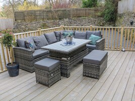 An outdoor patio with wicker furniture, a table, and a potted plant.