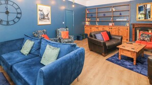 A living room with a blue sofa, a black leather armchair, a wooden coffee table, and a bookshelf. - Blue Ron's (High Peak)
