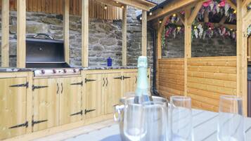 An outdoor bar area with a stone wall, wooden cabinets, and a grill.