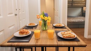 A breakfast table with croissants, orange juice, and a vase of flowers. - 2 The Glade (Bude)