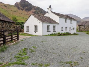 A white house with a gravel driveway, stone walls, and a mountainous backdrop. - One Side House Farm (Ambleside)