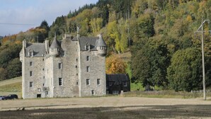 Un castello in pietra con numerose torri e un edificio più piccolo nelle vicinanze.