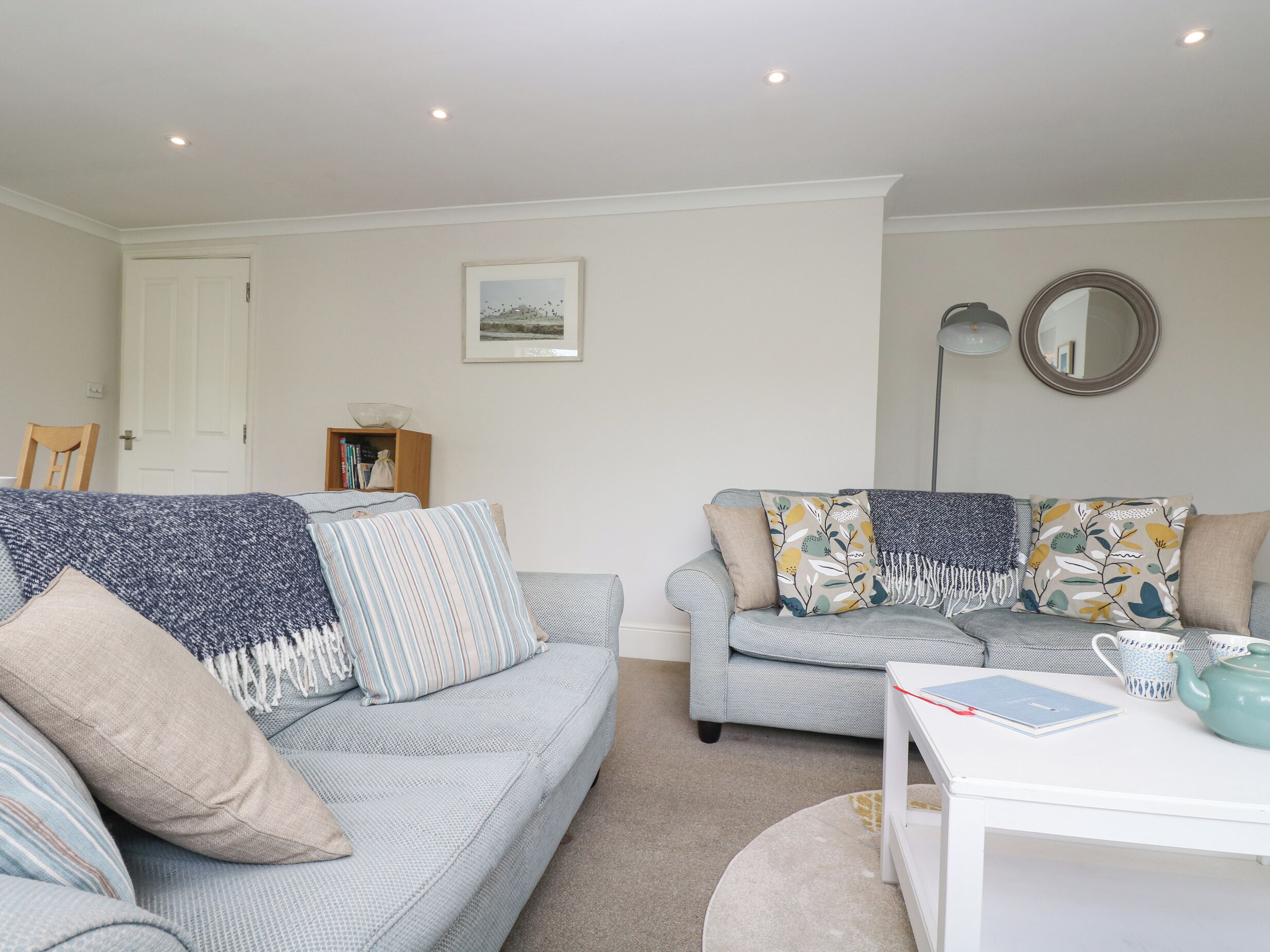 A living room with two sofas, a white table, a floor lamp, and a bookshelf.