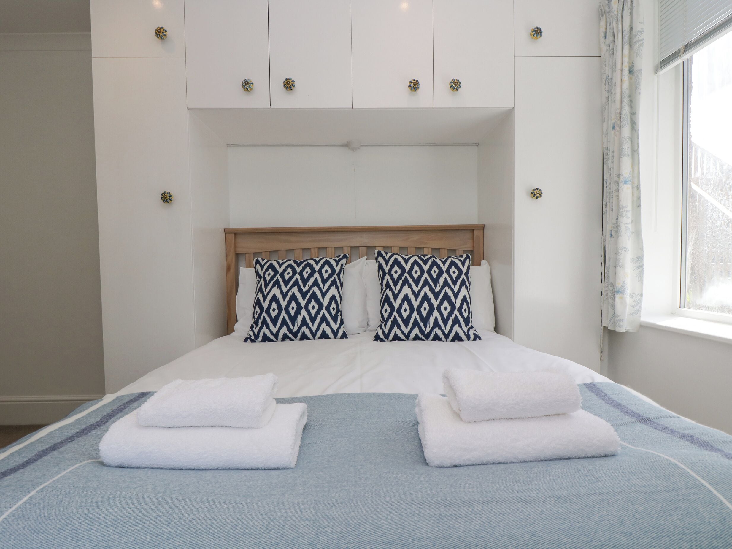 A neatly made bed with two pillows and two folded towels.