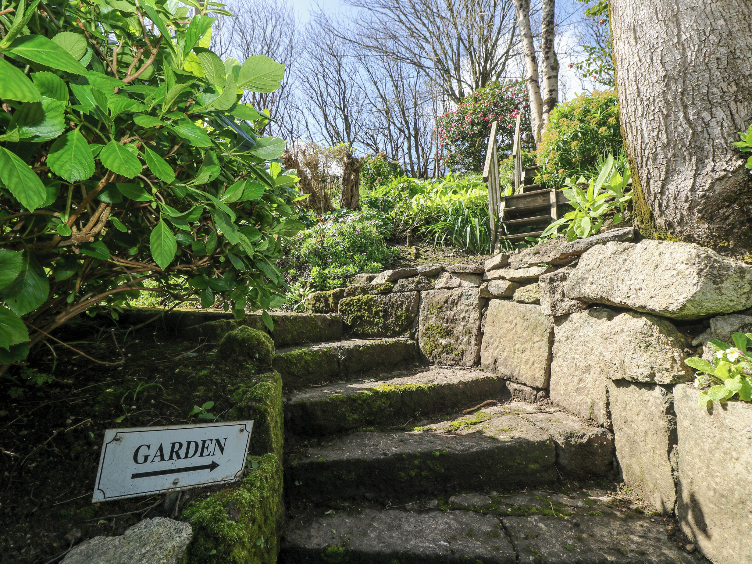 Stone steps leading to a garden area with a sign indicating the direction.