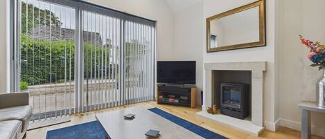 A modern living room with a sofa, a coffee table, a TV, and a fireplace.