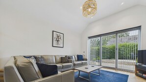 A modern living room with a grey sofa, a coffee table, and a large sliding glass door leading to a balcony. - Oakwood Lodge (Matlock)