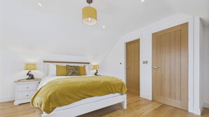 A bedroom with a bed, nightstands, a lamp, a wooden door, and a ceiling light. - Oakwood Lodge (Matlock)