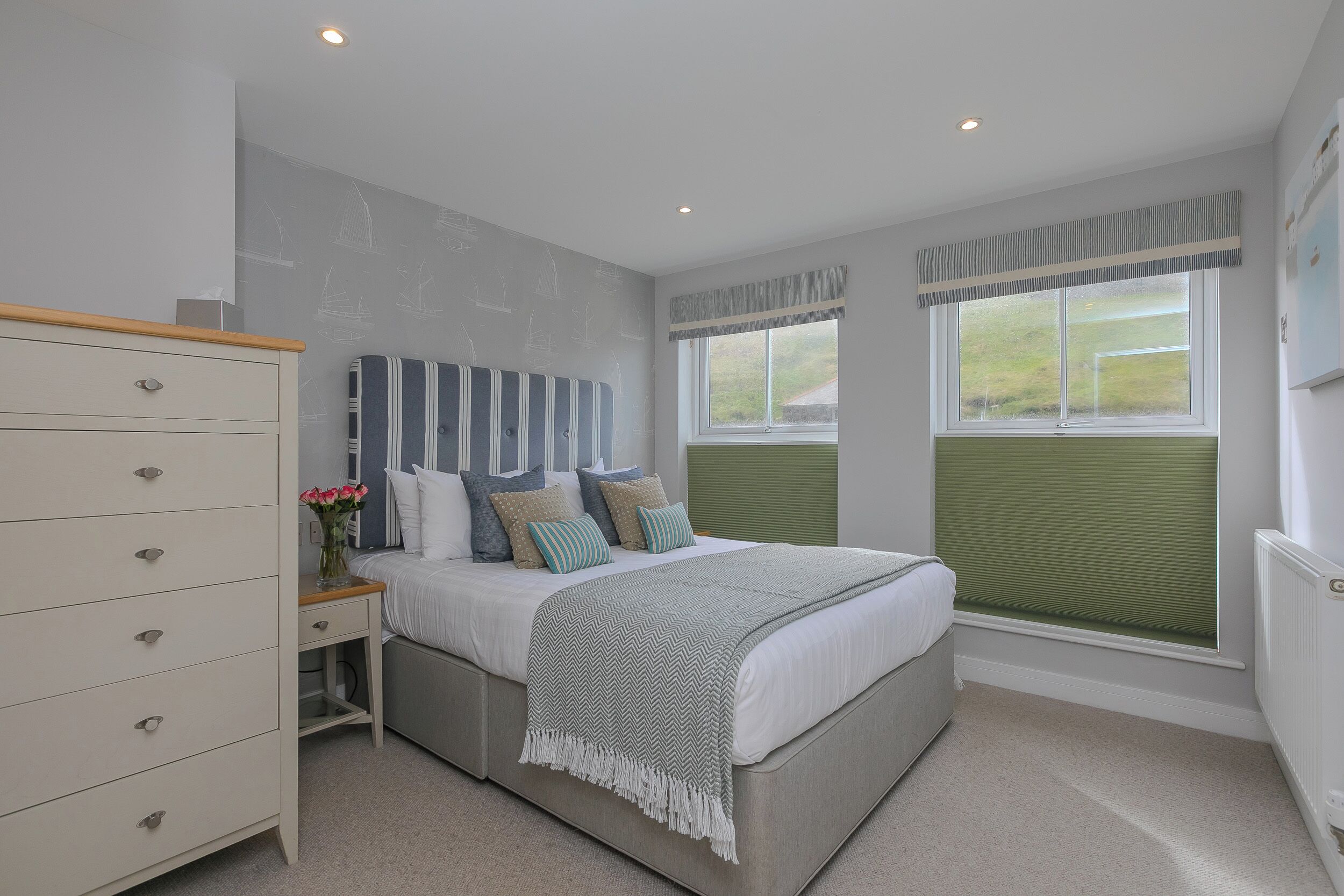 A bedroom with a bed, a dresser, and a window with blinds.