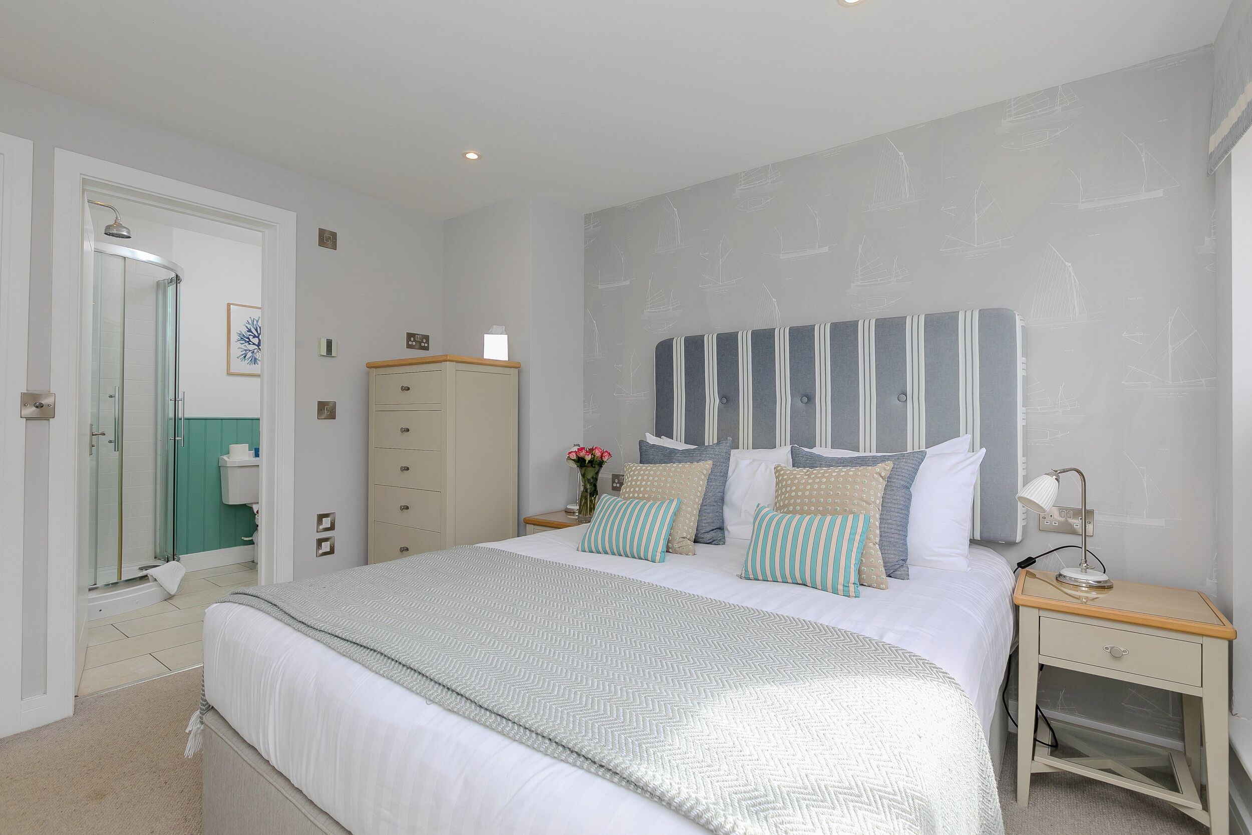 A bedroom with a bed, bedside table, nightstand, and a wardrobe.