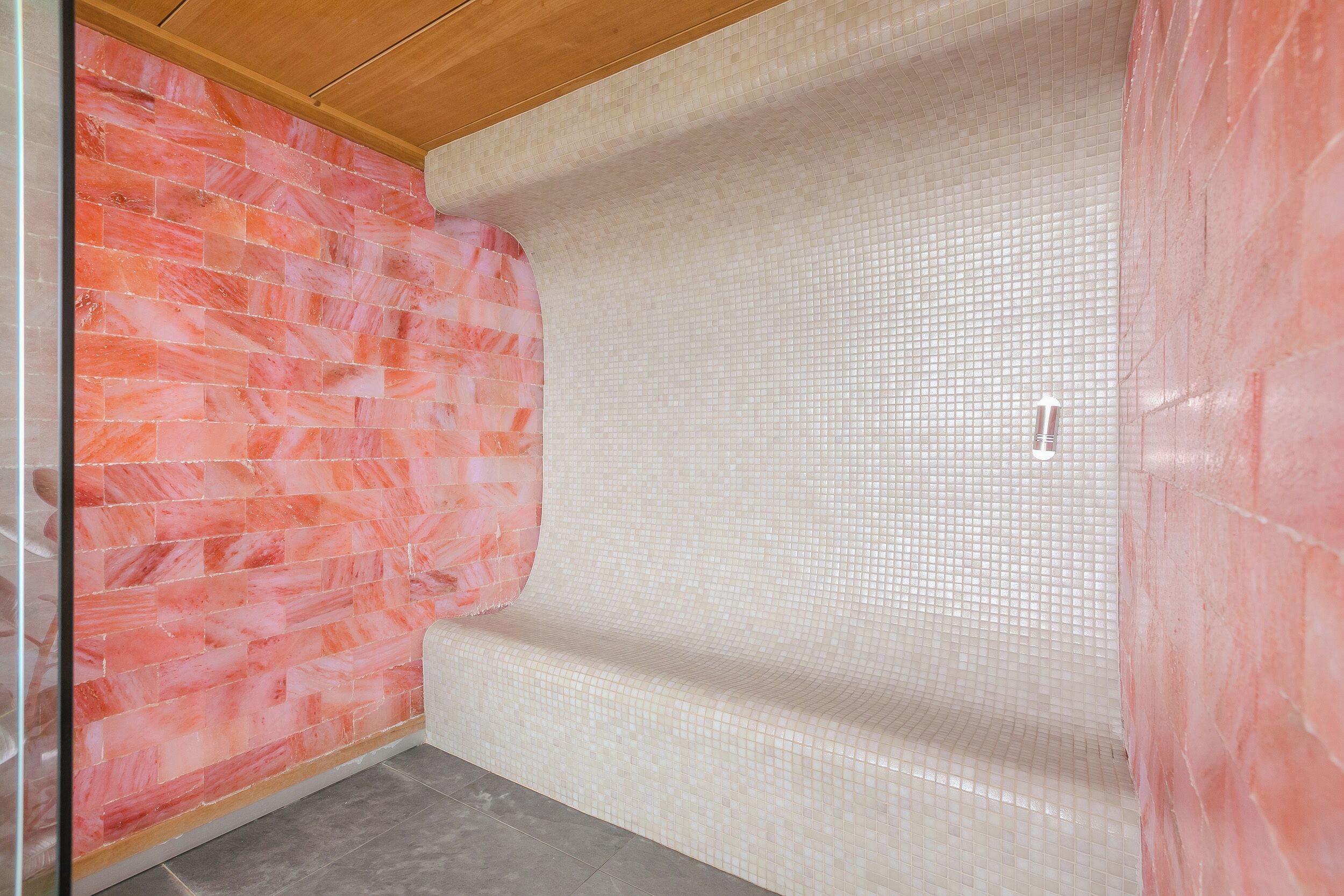A room with a tiled wall, a tiled floor, and a wooden ceiling.