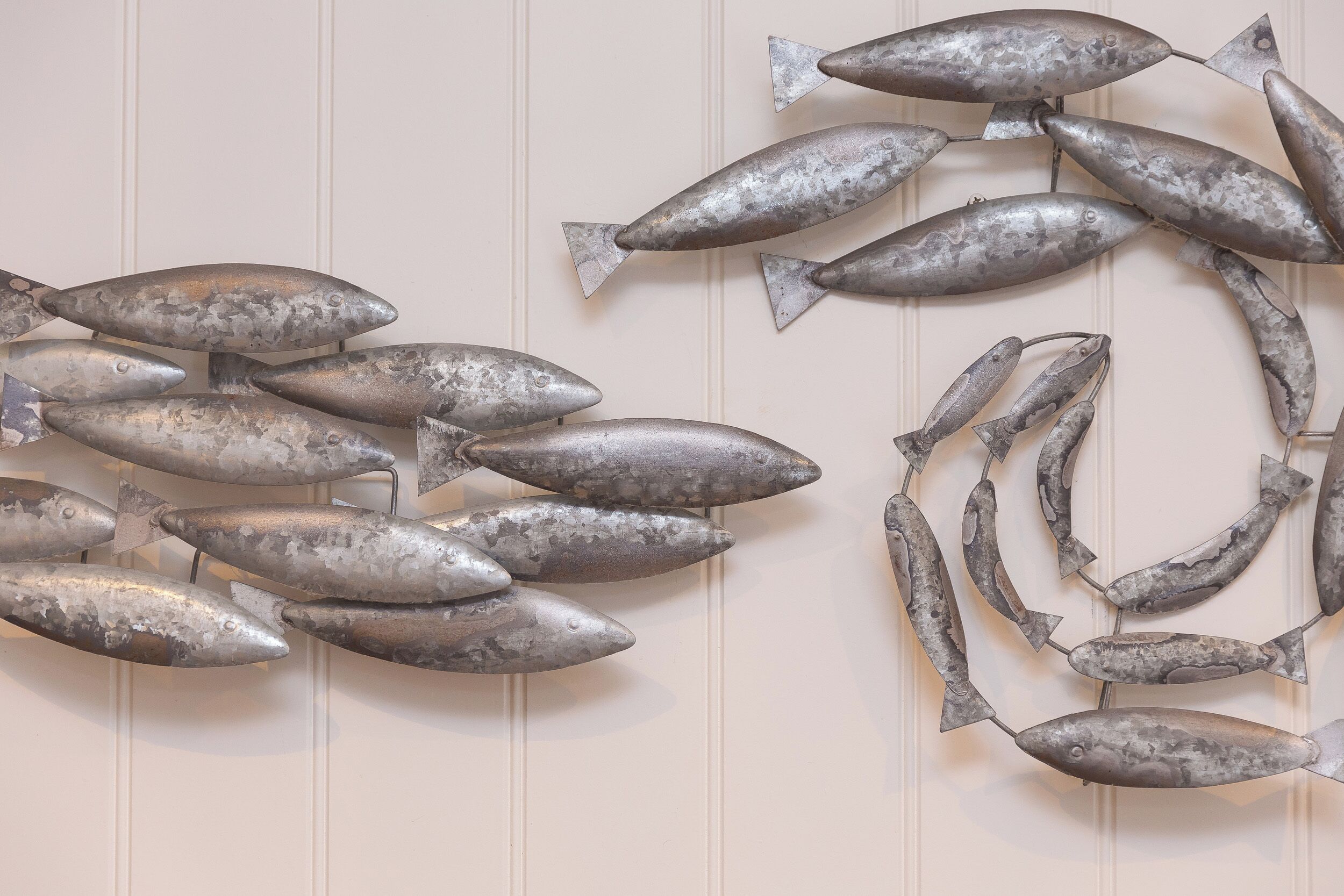Paredes decoradas com fileiras de esculturas metálicas de peixes.