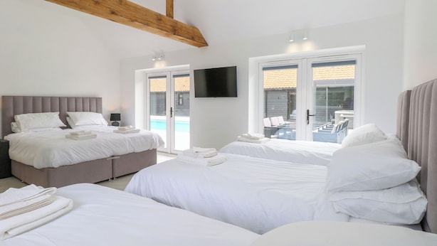 A hotel room with two beds, a TV, and a view of a swimming pool. - County Farm Barn (Norwich)