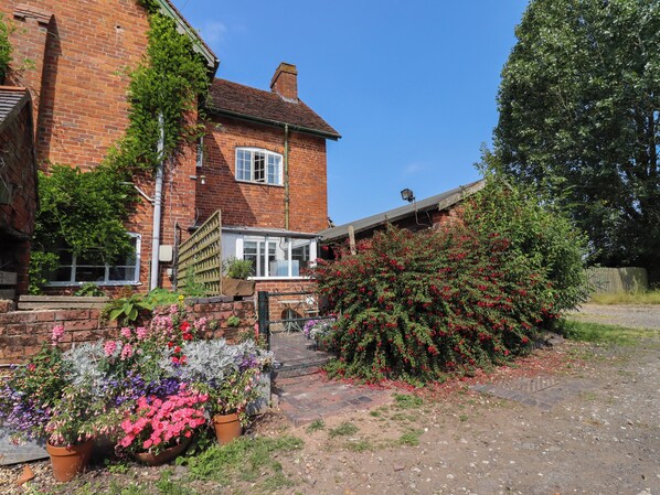 A brick house with a garden in front. - The Shires at Bickerscourt (Solihull)