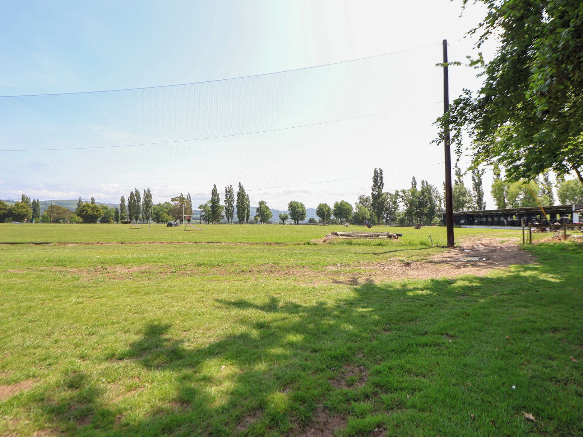 A grassy field with a wooden structure and a utility pole.