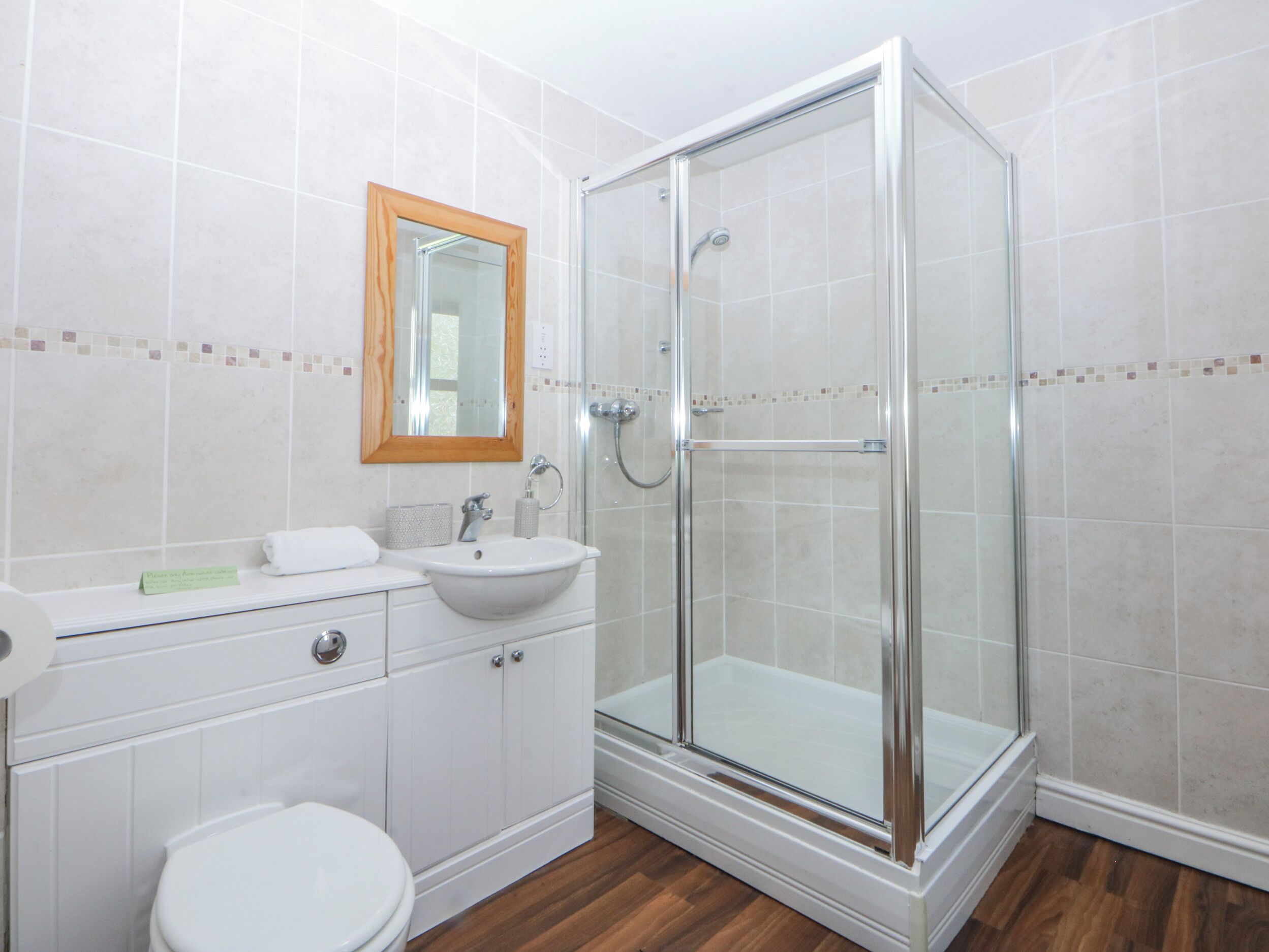 Ein Badezimmer mit Dusche, Waschbecken, Toilette und Spiegel.