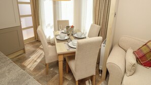 Un coin repas avec une table mise pour quatre personnes, comprenant des assiettes, des verres et un seau contenant une bouteille.