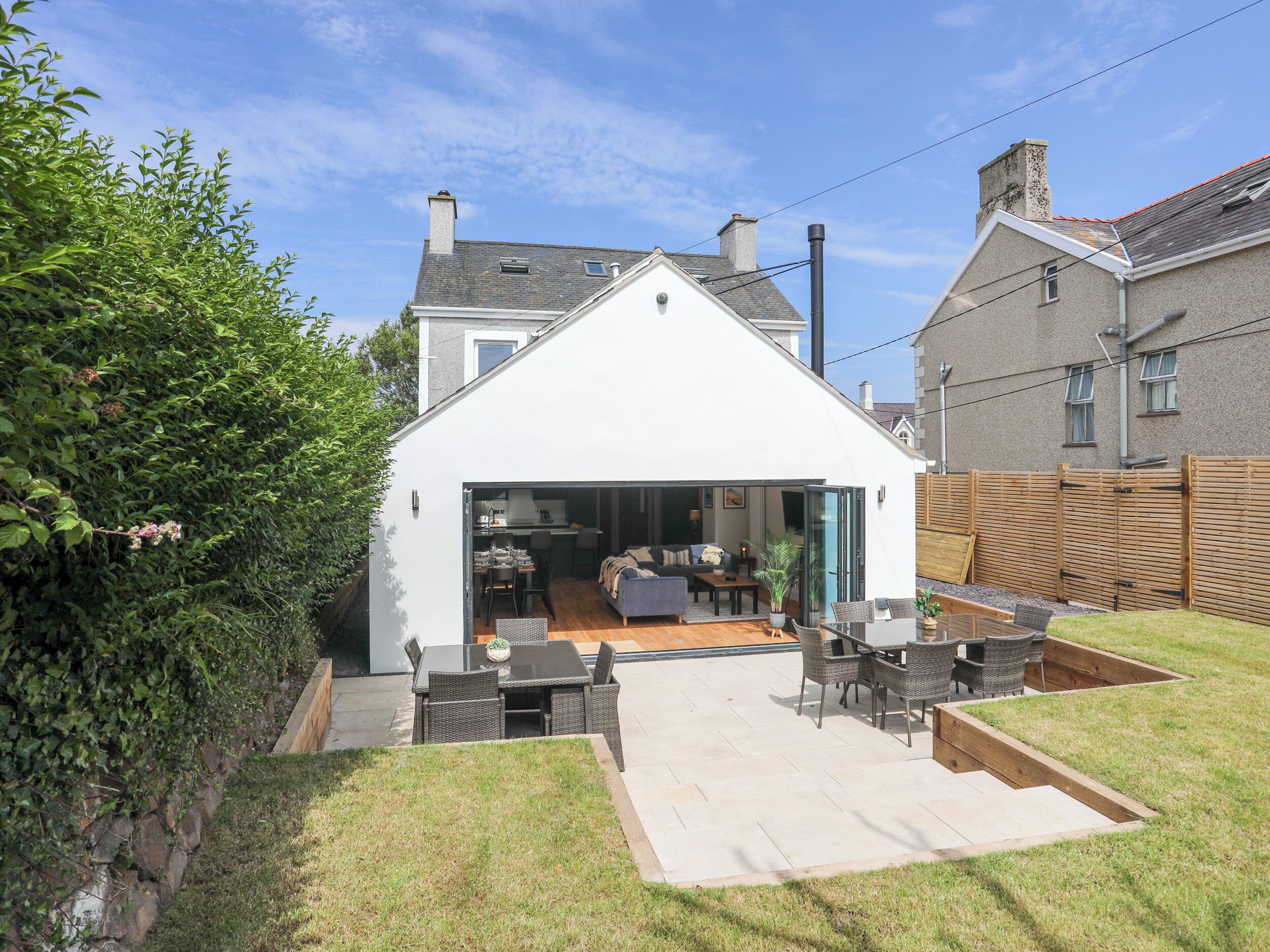 A modern house with a large patio area, a dining table, and a seating arrangement.
