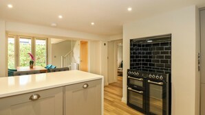 A modern kitchen with a large island, black tiled backsplash, and stainless steel appliances. - Daisy's Place (Fakenham)