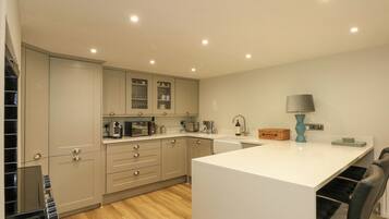 A modern kitchen with light-colored cabinets, a central island, and a black chair.