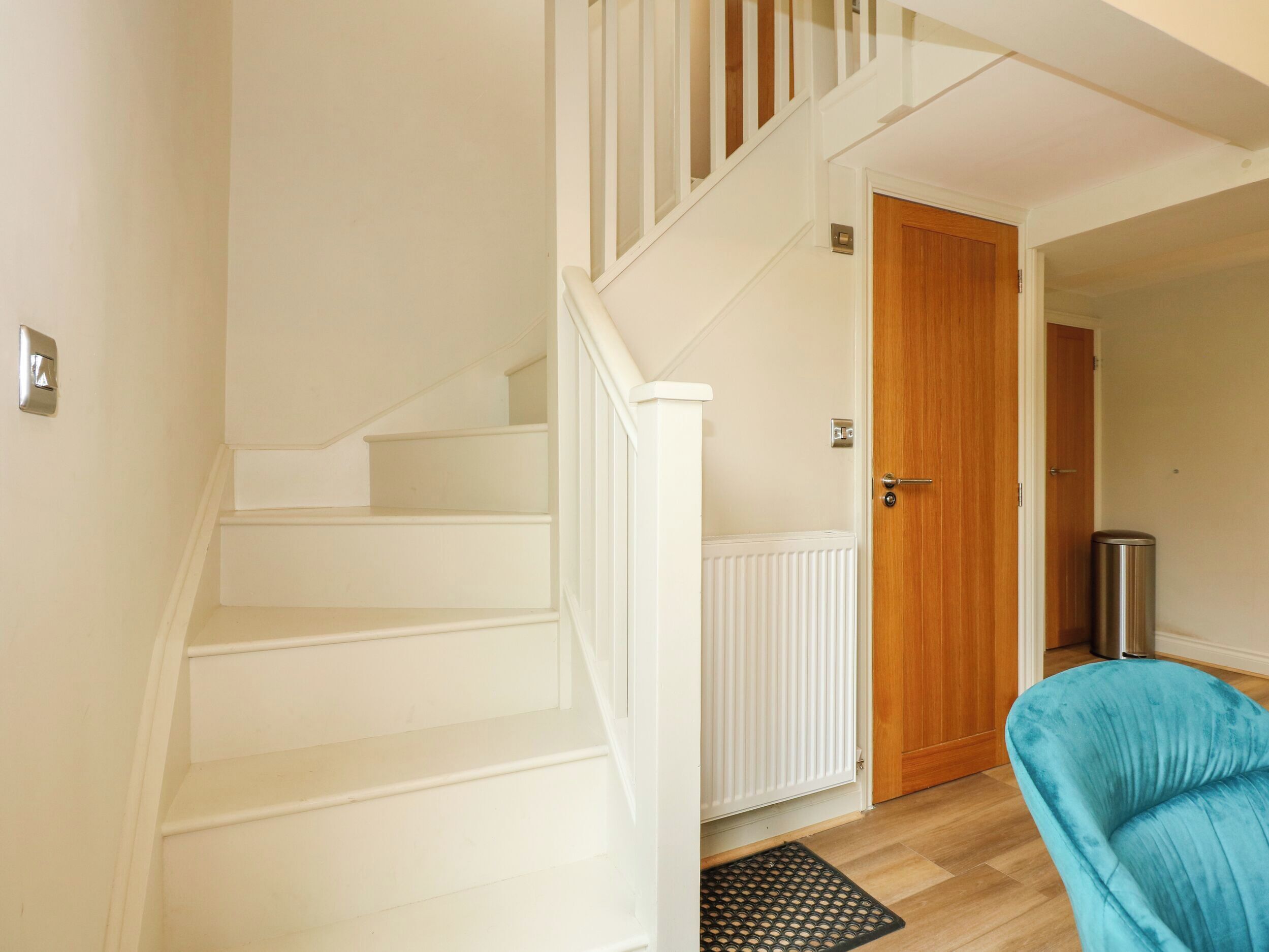A staircase with white walls and a wooden door at the top.