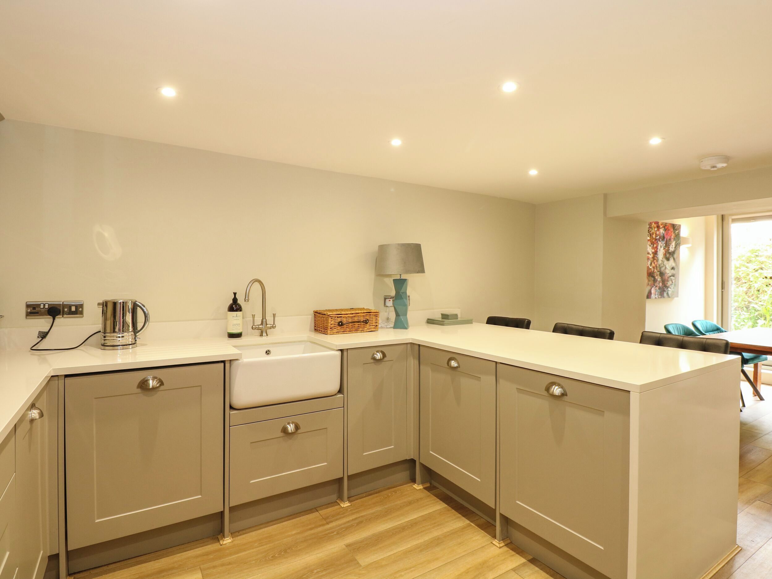 A modern kitchen with a built-in sink, a kettle, and a lamp on the counter.