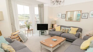 A modern living room with grey sofas, a wooden coffee table, and a flat-screen TV. - Leylands (Salcombe)