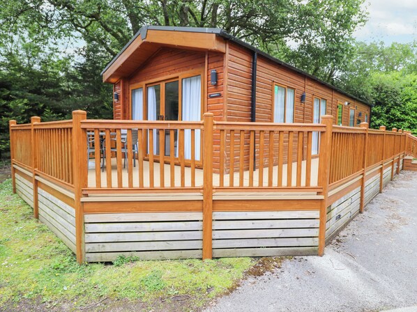 A wooden cabin with a deck, large windows, and a sign that reads "CAMPER". - Tawny Owl Lodge (Windermere)