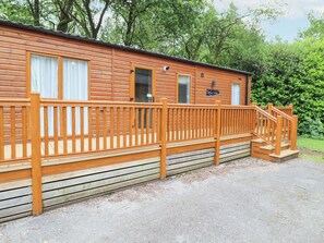 A wooden cabin with a wooden deck and a staircase leading to the entrance. - Tawny Owl Lodge (Windermere)