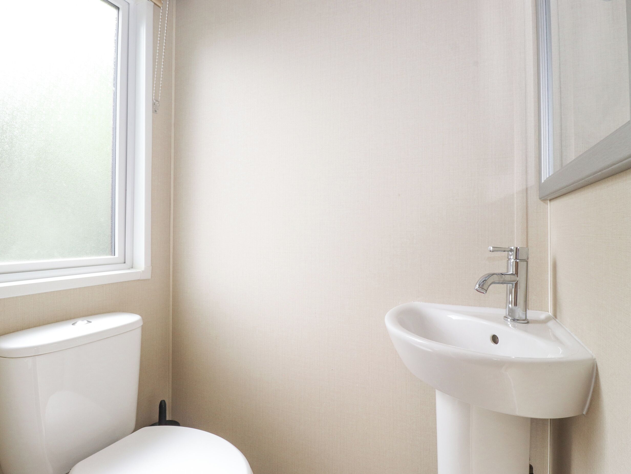A bathroom with a toilet, sink, and window.