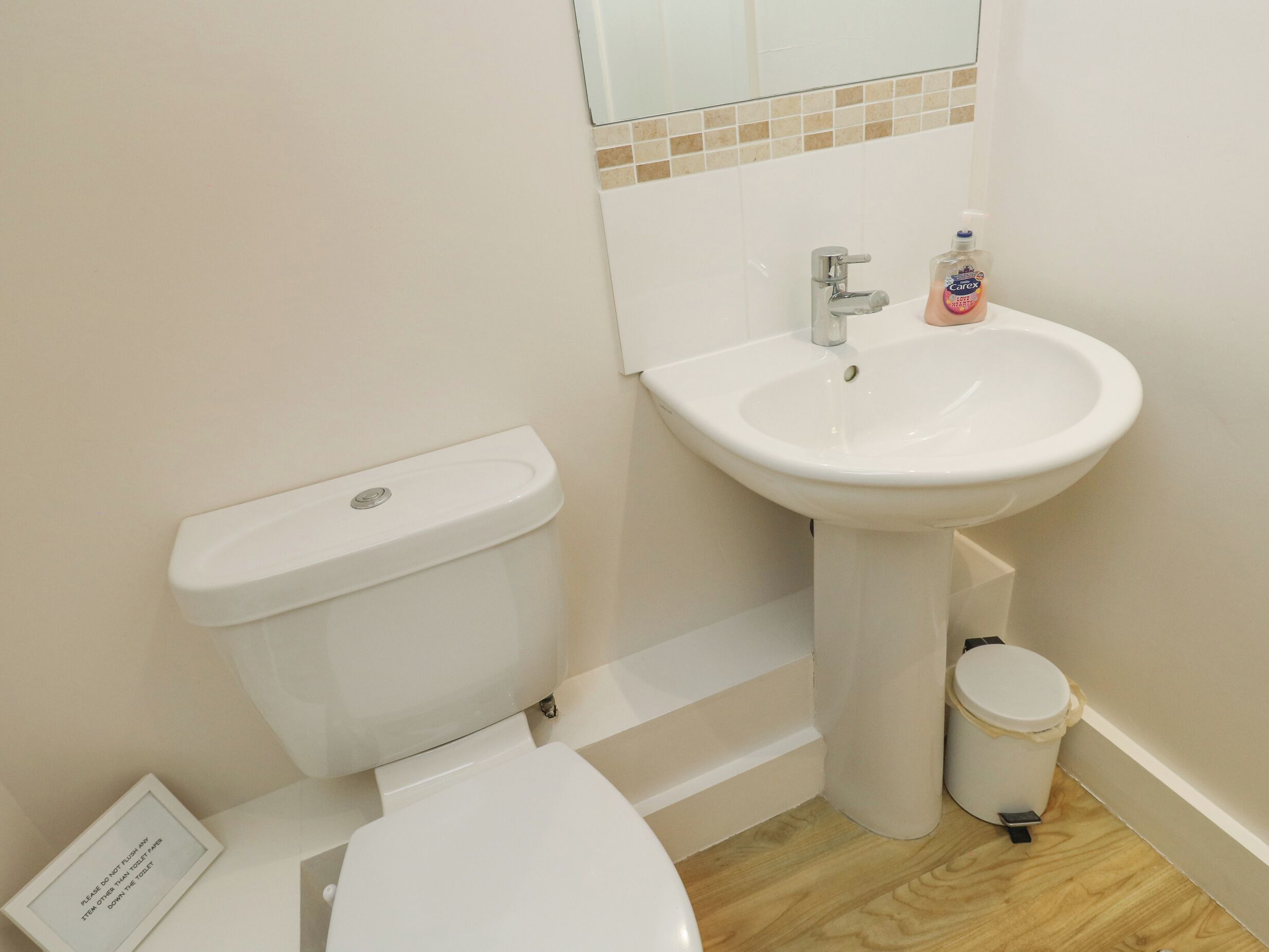 A bathroom with a toilet, sink, and a trash bin.