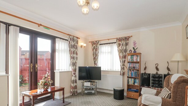 A living room with a sofa, a TV, a bookshelf, and a window with curtains. - Fatima (Burnham-on-Sea)