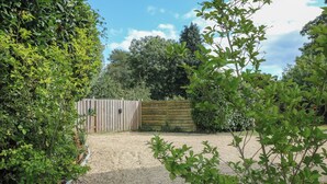 A gravel driveway leading to a wooden gate, surrounded by lush greenery and a clear sky. - 2 Welford Barns (Fordingbridge)