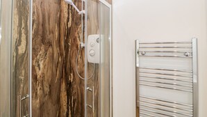 A shower with a glass door, a handheld showerhead, and a control panel. - 2 Welford Barns (Fordingbridge)