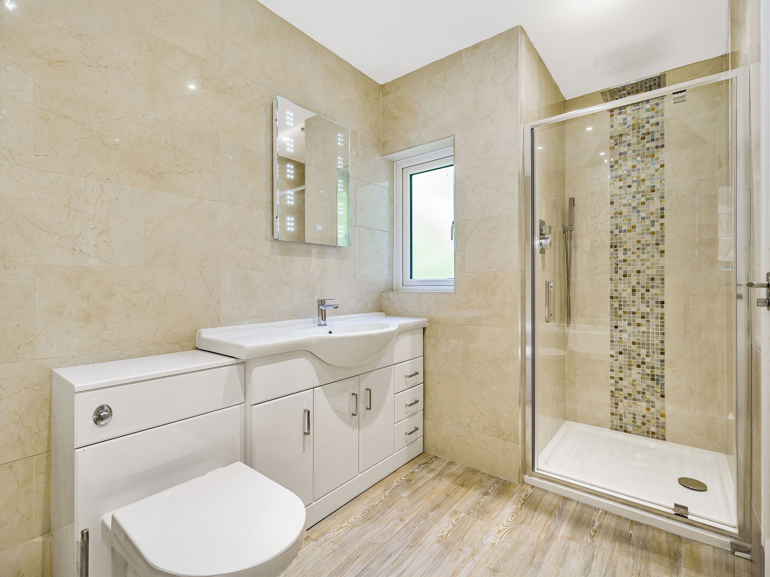 Un baño moderno con cabina de ducha de vidrio, un lavamanos blanco y un inodoro.