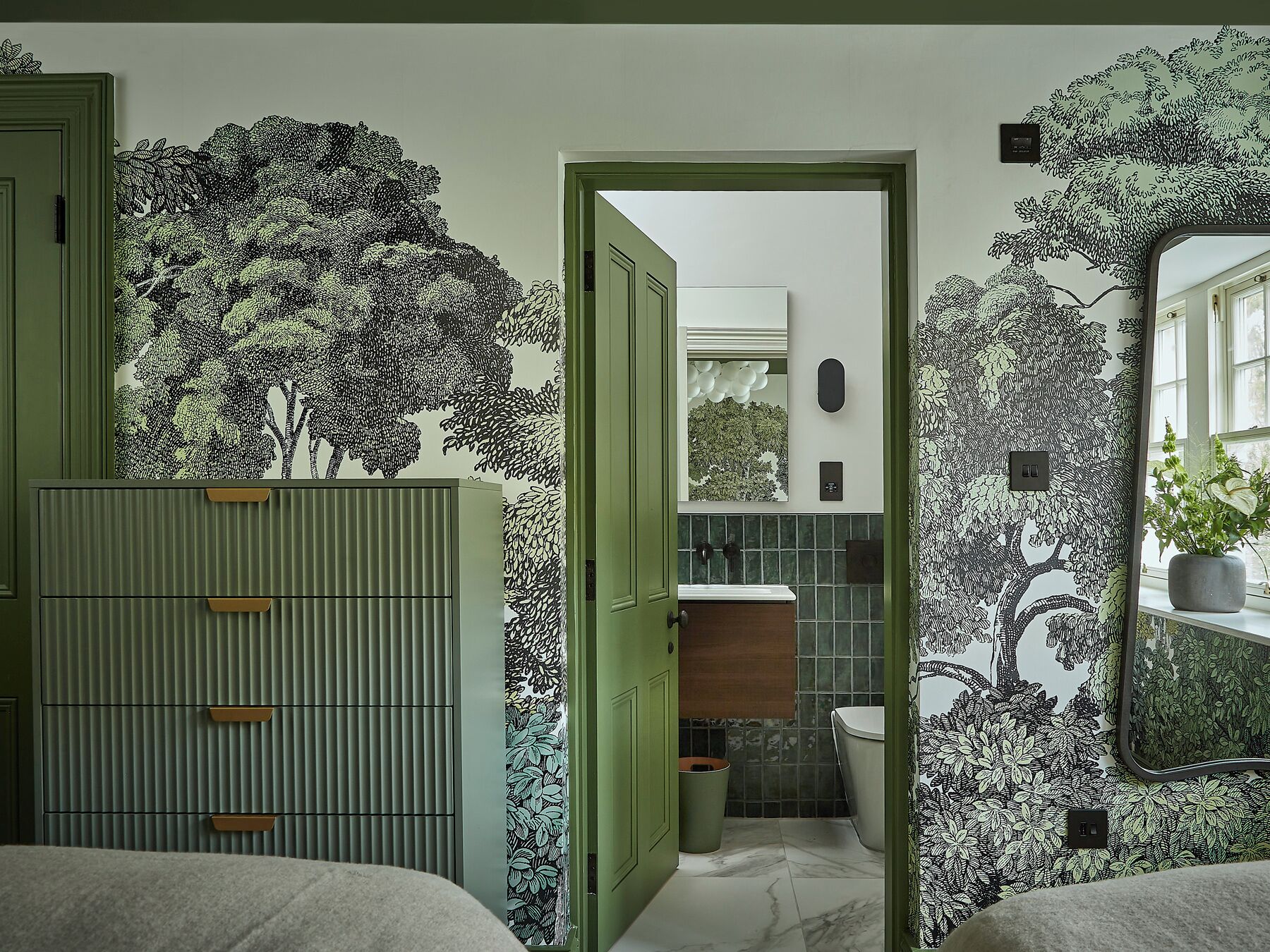 A bathroom with a green door, a mirror, a sink, and a toilet.