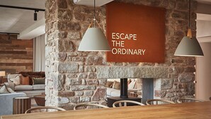 A dining area with a stone wall, a wooden table, and two pendant lights. - Eskdale Retreat (Holmrook)