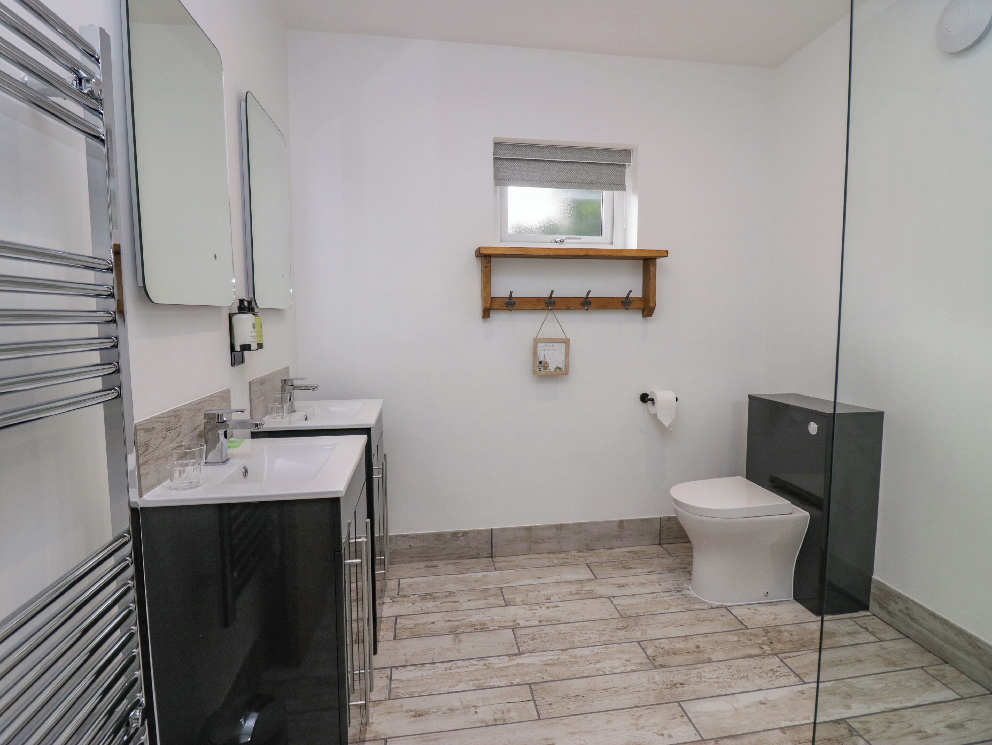 Ein modernes Badezimmer mit zwei Waschbecken, einer Toilette und einer Duschkabine.