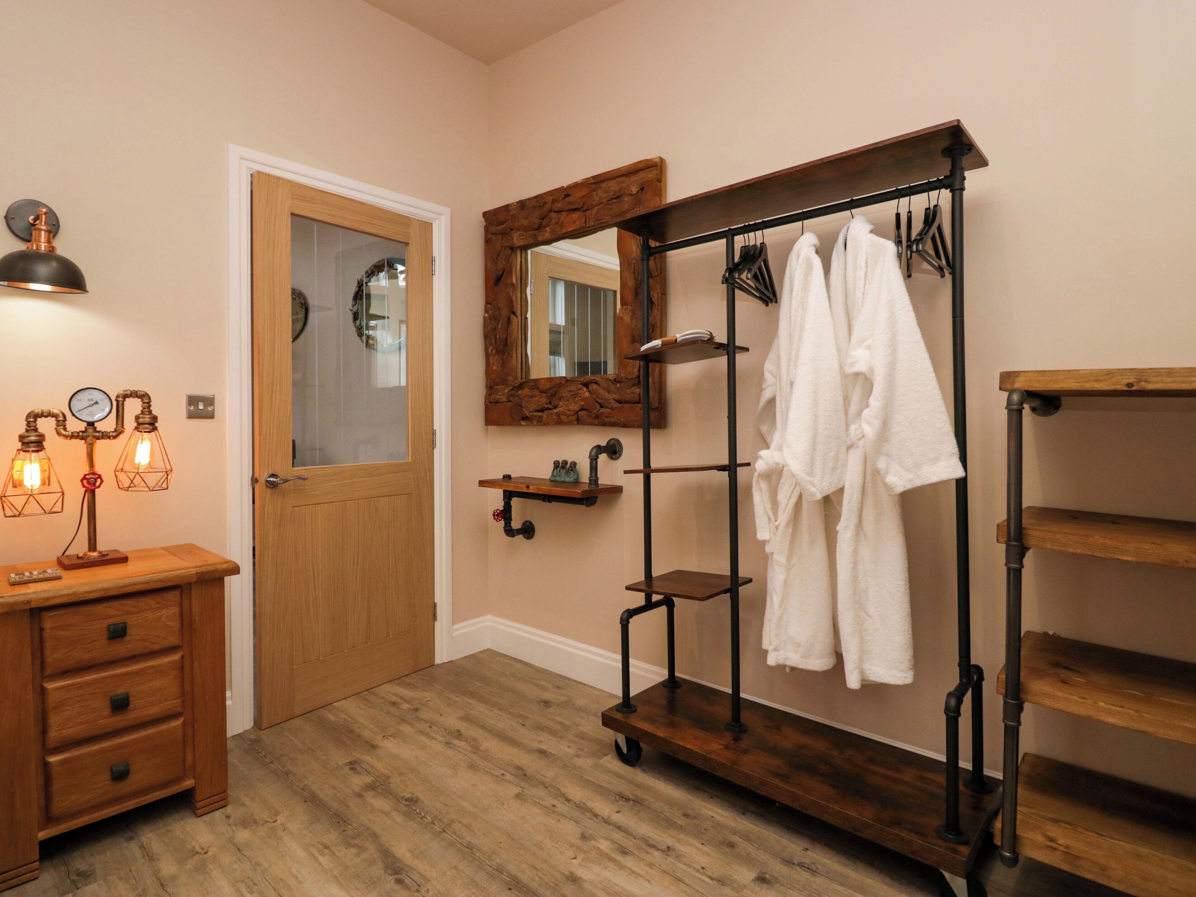 A bathroom with a wooden vanity, a towel rack, a mirror, and a shelf with towels.