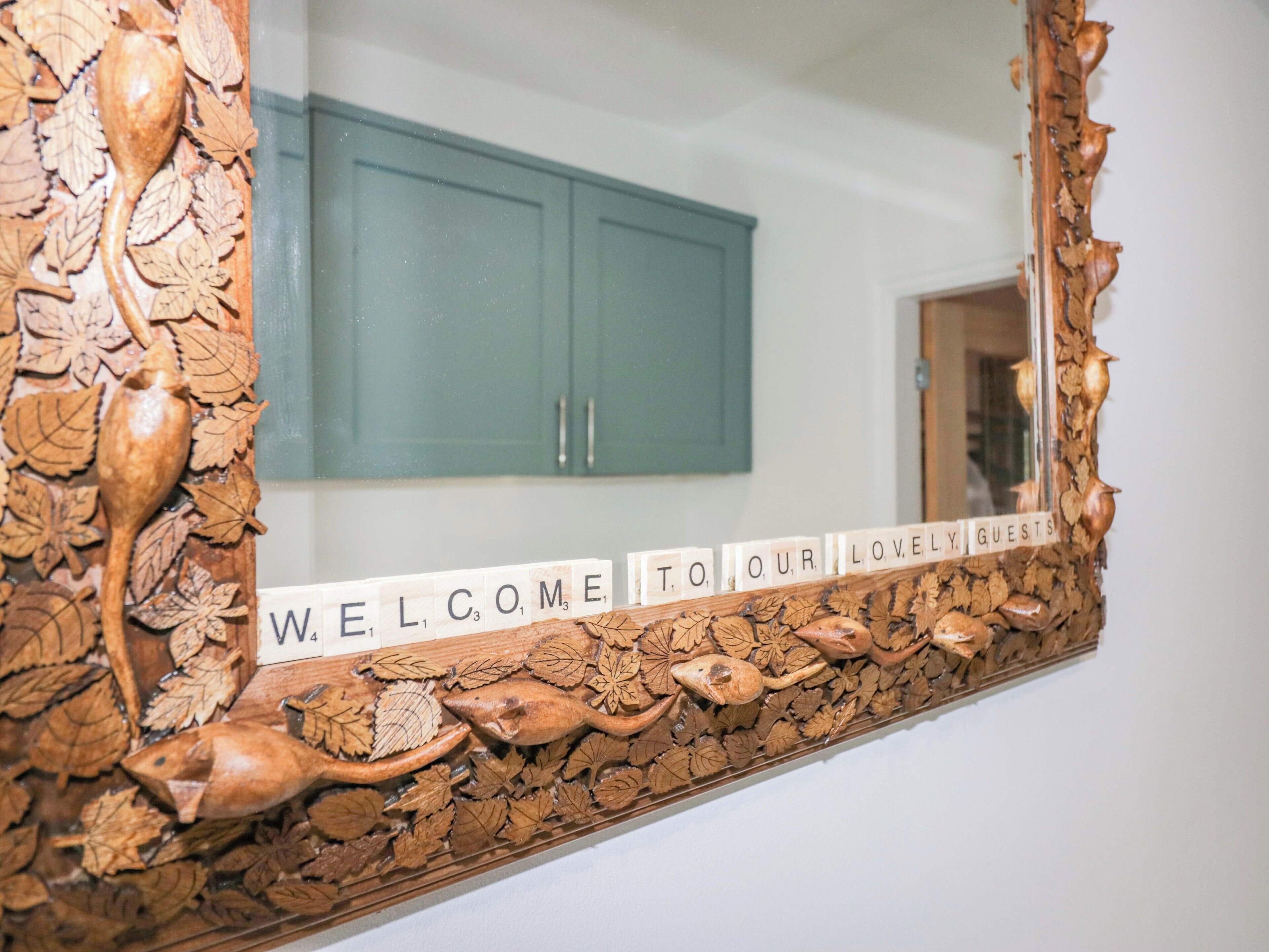 A wooden wall with carved leaves and a welcome sign.