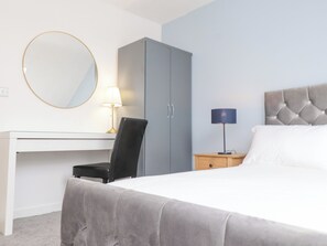 A bedroom with a bed, a desk, a chair, a wardrobe, and two bedside lamps. - Blue Bay Villa (Holyhead)