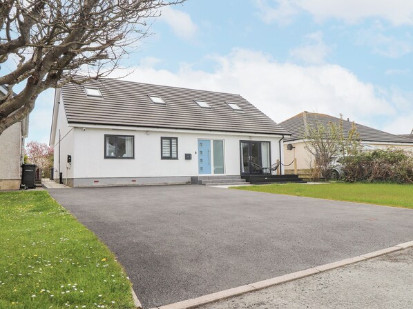 A single-story house with a grey roof, a blue door, and a small front porch. - Blue Bay Villa (Holyhead)
