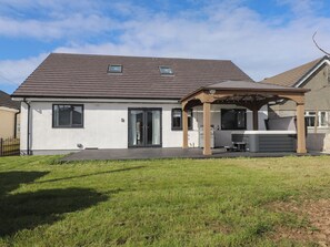 A modern house with a covered patio, a large window, and a garage. - Blue Bay Villa (Holyhead)