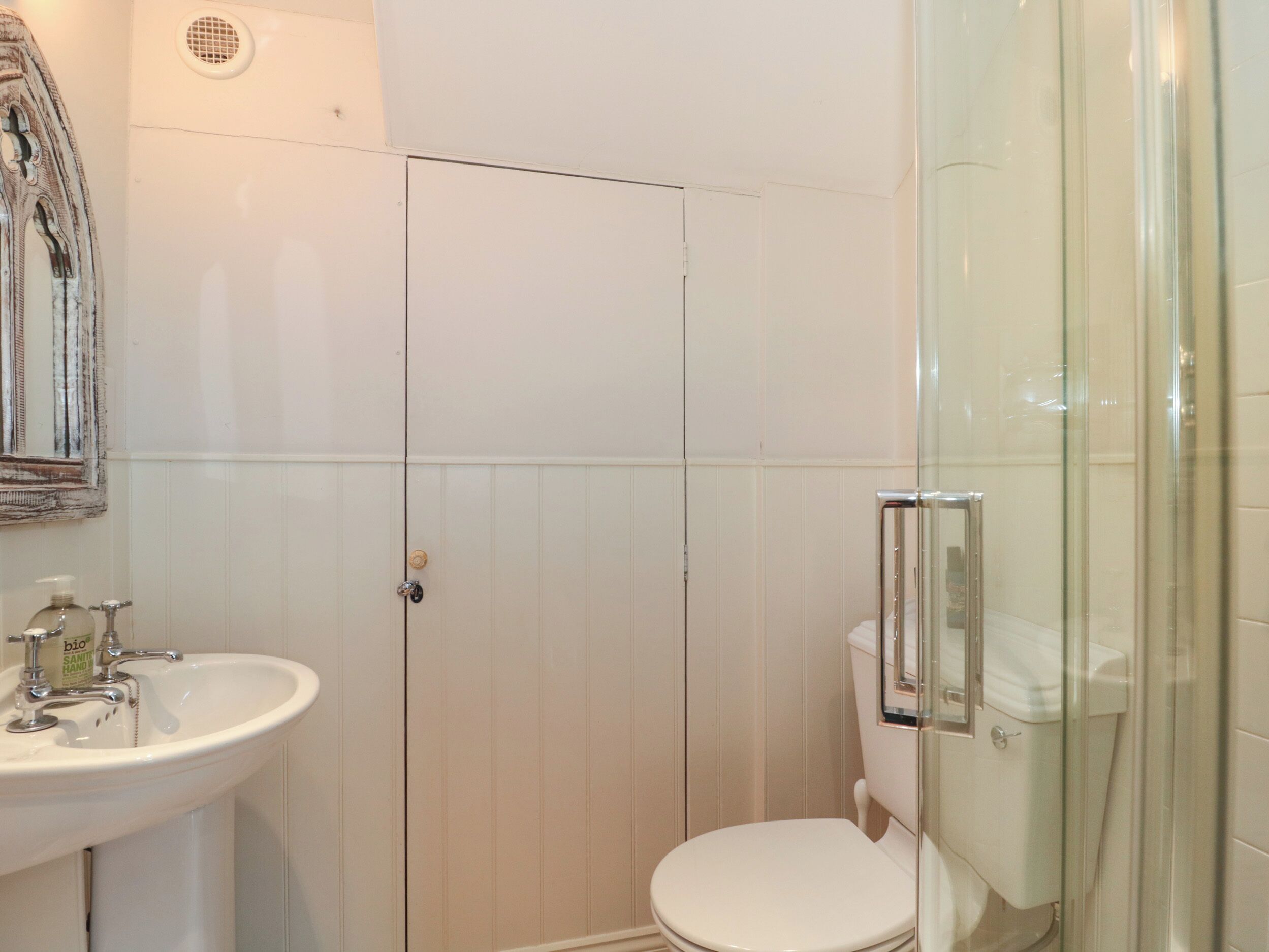 A bathroom with a white sink, toilet, and glass shower enclosure.